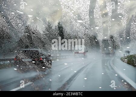 Pare-brise mouillé par la pluie bloque la vue de la route / dangereux voiture floue par temps pluvieux Banque D'Images