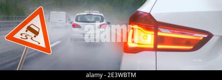 Risque d'accidents sous la pluie et le brouillard sur l'autoroute avec des voitures au freinage et des panneaux de signalisation en dérapage Banque D'Images