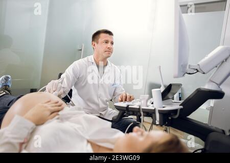 Portrait d'un médecin obstétricien professionnel hautement qualifié qui examine la femme enceinte par échographie. Femme enceinte ayant le dépistage ultrasonique Banque D'Images