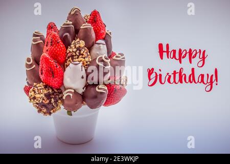 Carte de voeux pour joyeux anniversaire avec inscriptions rouges ; BOUQUET de fleurs comestibles, arrangement de fraises enrobées de chocolat isolées sur fond blanc Banque D'Images