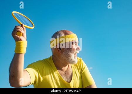 Homme âgé pratiquant le tennis sur fond bleu ciel. Homme senior joueur de tennis Banque D'Images