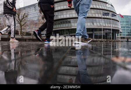 Londres, Royaume-Uni. 20 janvier 2021. Un reflet des hommes qui marchent le long de Potters Fields Park où habituellement utilisé pour des festivals de nourriture et d'autres événements, en passant devant l'hôtel de ville à Londres, Royaume-Uni, le 20 janvier 2021. Les prévisions du bureau de rencontre la seule journée ensoleillée à Londres dans les 7 prochains jours devrait être le vendredi 22 janvier crédit : May James/ZUMA Wire/Alamy Live News Banque D'Images