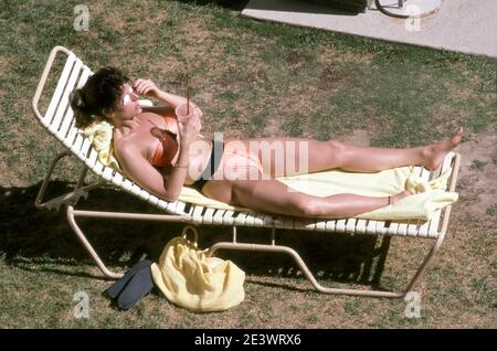 Femme bronzant sur la pelouse près de la piscine à l'hôtel Riviera à Las Vegas, Nevada vers 1990. Banque D'Images