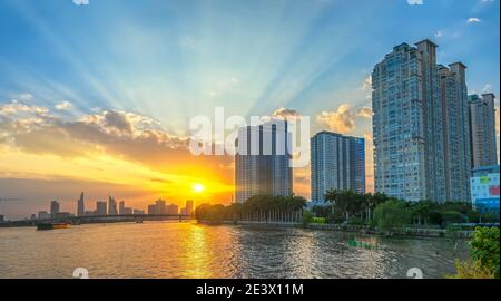 Coucher de soleil dans les zones urbaines le long de la rivière avec des gratte-ciels lire l'éclat par le ciel dramatique créer la beauté du développement urbain à Ho Chi Minh ville, Vietnam