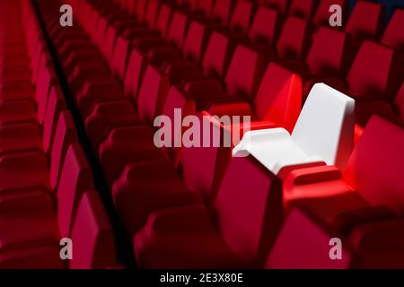 La 3D rend les mêmes rangées de chaises souples de dessin animé rouge et une chaise blanche dans le théâtre. Concept d'un beau cinéma au néon avec chaises Banque D'Images