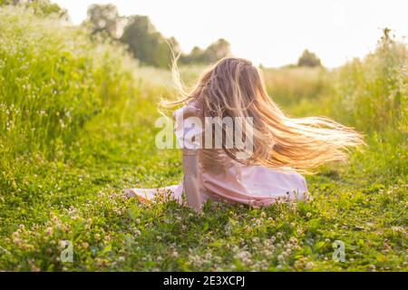 fille assise sur le terrain dans une robe rose Banque D'Images