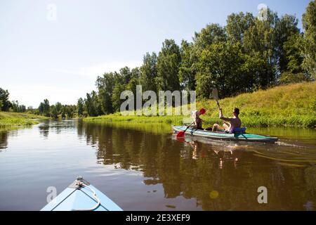 Un couple d'hommes et de femmes font du kayak sur la rivière en été. Loisirs actifs, voyages en famille, aventure extrême, sports et environnement domestique touris Banque D'Images