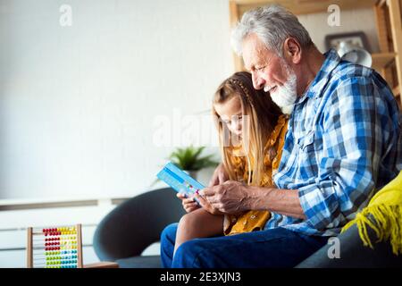 Grand-père barbu et son petit-fils ont du plaisir de lire un livre ensemble Banque D'Images