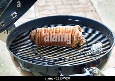 Porchetta étant cuit sur le barbecue et arrosé d'olive huile Banque D'Images