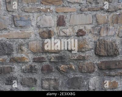 Mur avec maçonnerie de pierre rugueuse de formes diverses et épaisse couche grise de ciment entre eux. Texture non homogène Banque D'Images