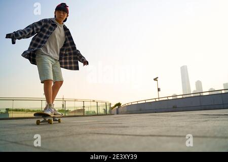 enfant asiatique adolescent skate à l'extérieur sur un pont piétonnier Banque D'Images