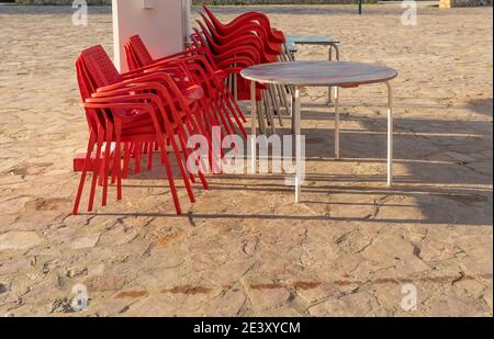 Chaises en plastique rouge empilées à l'extérieur d'une cafétéria fermée par la crise du coronavirus. Arrière-plan de l'image hors foyer. Restrictions dans la restauration Banque D'Images