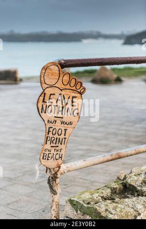 Un panneau en bois fait à la main vous demandant de ne laisser que votre empreinte sur la plage attachée aux rampes de Little Fistral à Newquay en Cornouailles. Banque D'Images