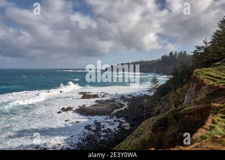 Vue sur la baie de Cresswell et son littoral spectaculaire avec des vagues qui s'écrasent contre les rochers avec le soleil éclatant et le nuage brisé, île Norfolk, Australie Banque D'Images
