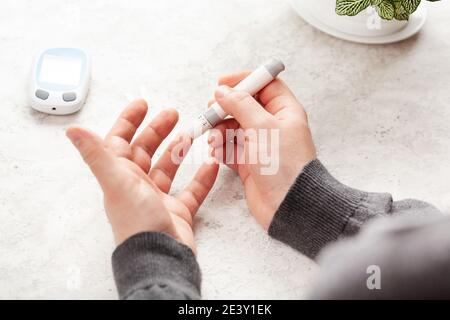 mains de l'homme utilisant lancet sur le doigt pour vérifier le taux de sucre ou de cétones dans le sang par le glucomètre. médecine diabète keto régime de soins de santé à la maison Banque D'Images