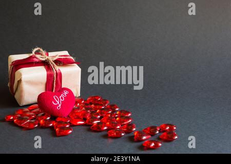 Cœur rouge et boîte cadeau sur fond noir - Saint-Valentin, bannière, espace publicitaire. Shopping pour un être cher, un couple amoureux Banque D'Images