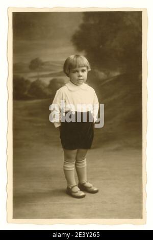 Original début 1900, photo de portrait de studio de garçon âgé d'environ 3 ans avec bob hairstyle, debout regardant sérieux, Royaume-Uni vers 1925 Banque D'Images
