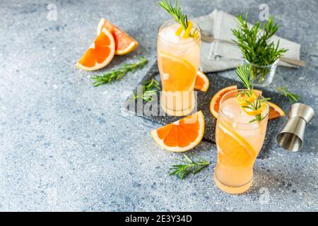 Deux verres de cocktails Paloma avec jus de pamplemousse frais et romarin. La boisson festive est idéale pour le brunch, les fêtes et les vacances. Banque D'Images