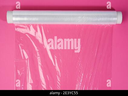 rouleau de film adhésif transparent sur fond rose pour l'emballage des produits, vue de dessus Banque D'Images
