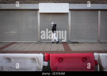 Un homme marche le long de Green Street dans l'est de Londres, une rue commerçante normalement fréquentée qui est maintenant une route de boutiques à bord, pendant le troisième confinement national de l'Angleterre pour freiner la propagation du coronavirus. Date de la photo: Jeudi 21 janvier 2021. Banque D'Images