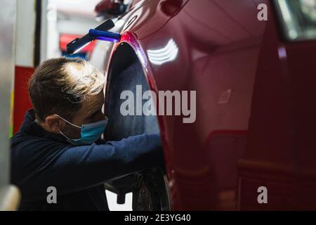 mécanicien répare la suspension de voiture. Concentrez-vous sur les mains. COVID 19 Banque D'Images