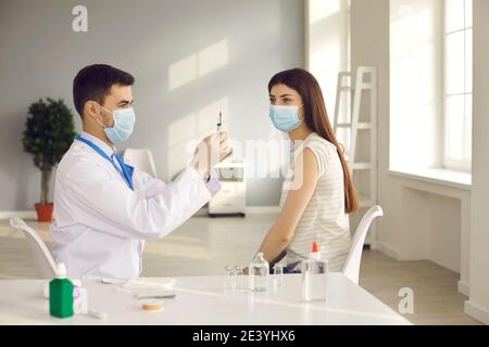 Homme médecin en uniforme et masque médical préparant la seringue avant faire la vaccination Banque D'Images