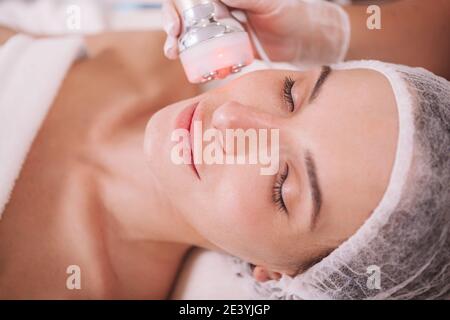 Gros plan d'une belle femme recevant un soin de levage de rf facial par esthéticienne. Rajeunissement, dorloter concept Banque D'Images