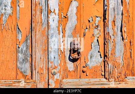 Le knocker de porte antique et l'ancienne porte en bois avec la peinture ébréchée vont parfaitement ensemble. Banque D'Images