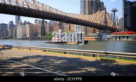 New York, NY, États-Unis - 20 janvier 2021 : bateau à remorqueurs poussant une barge sur la rivière East sous le pont Queensboro, vu de Roosevelt Island Banque D'Images