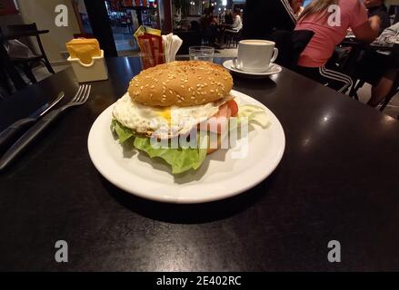 dans une assiette sur une table sombre, compléter le hamburger ou le hamburger à viande hachée avec des œufs, des tomates et de la laitue Banque D'Images
