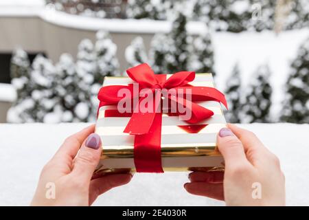 Les mains des femmes tiennent un cadeau de Noël. Tradition d'échange de cadeaux. Banque D'Images