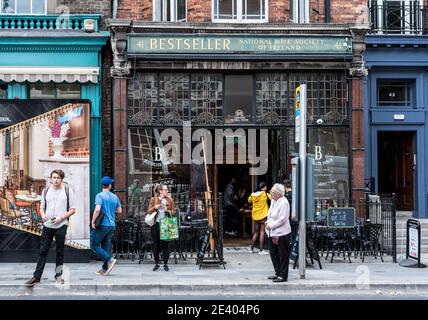 Dublin, Irlande--16 juillet 2018. Les gens se tiennent devant un bar à vin de Dublin, dont une femme dans une veste rose, apparemment en attente d'un bus. Banque D'Images