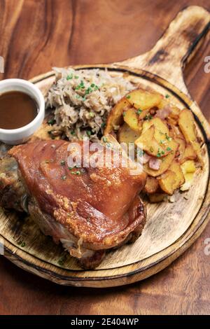 SCHWEINSHAX porte-jarret de porc allemand traditionnel avec choucroute et pommes de terre bavaroises repas sur fond de bois rustique Banque D'Images