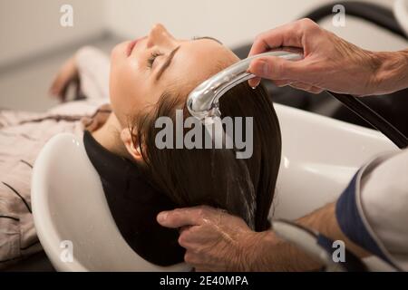 Photo courte en gros plan d'une femme lavée ses cheveux au salon de beauté. Coiffeur professionnel travaillant à son salon, se lavant les cheveux de lui Banque D'Images