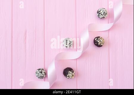 Bonbons faits main au chocolat sur table en bois rose avec ruban de fête avec place pour votre espace de copie de texte Banque D'Images