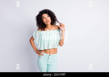 Photo portrait de fille rêveuse avec des lèvres de bosse jouant avec cheveux regardant l'espace vide isolé sur fond blanc coloré Banque D'Images