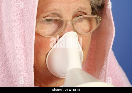 Femme malade de 65 ans en gros plan utilisant un inhalateur pour traiter les rhumes et mal de gorge Banque D'Images