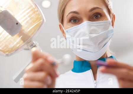 Gros plan POV d'un dentiste féminin tenant des outils dentaires pour l'examen oral. Dentiste professionnel travaillant à son bureau, examinant vos dents. OCC Banque D'Images