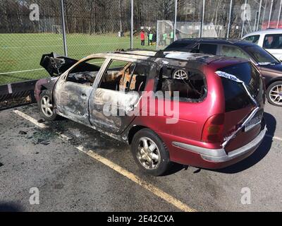 Stockholm, Suède - 29 avril 2016 : une voiture brûlée se tenant sur un parking à côté d'un terrain de flotball avec des joueurs jouant au flotball. Avec ruban de police o Banque D'Images