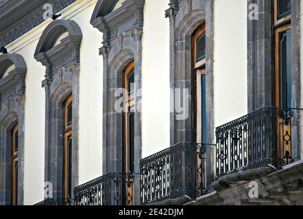 Fenêtres en pierre symétrique et balustrades de balcon en fer artisanal sur la façade de l'hôtel de ville de style colonial à Zacatlán de las manzanas, Mexique. Banque D'Images