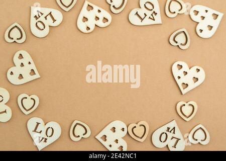Coeurs en bois sur fond de papier pastel, sous forme de cadre. Arrière-plan abstrait avec formes en bois. Sainte-Valentin. Copier l'espace. Banque D'Images