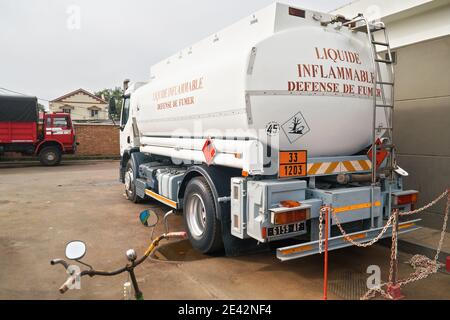 Moramanga, Madagascar - 25 avril 2019 : camion à essence blanc avec avertissement « inflammable » en français stationné à la station-service locale, une autre grande voiture à l'arrière-plan Banque D'Images