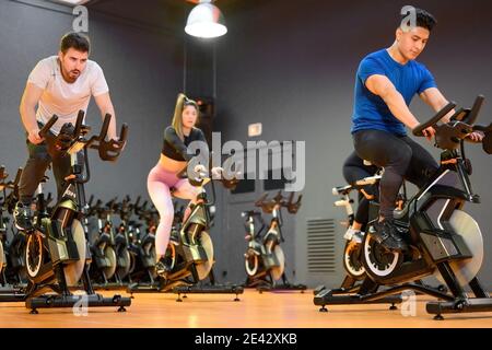 Faites du vélo de groupe sur un vélo de fitness moderne pendant un cours de spinning de groupe à la salle de sport. Photo de haute qualité Banque D'Images