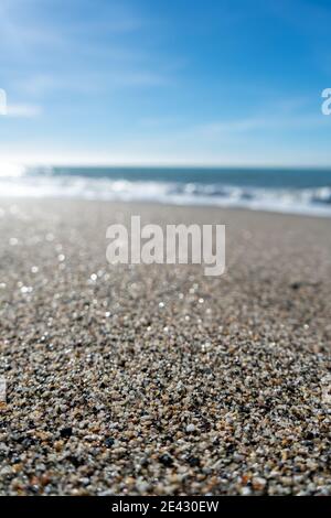 Gros plan de grains de sable sur une plage avec flou littoral et horizon en arrière-plan Banque D'Images