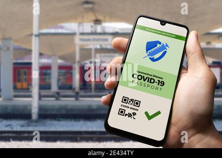 Passeport de vaccination pour le COVID-19 affiché sur smartphone tenu dans la main d'homme à la gare ferroviaire. Vaccination, maladie immunité passeport, santé et Banque D'Images