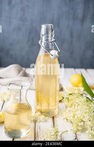 Boisson rafraîchissante saine et délicieuse, sirop de sureau doux ou cordial dans une bouteille de verre sur fond rustique en bois Banque D'Images