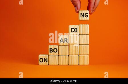 Symbole du processus d'intégration réussi. Cubes en bois empilés comme escalier sur fond orange, espace de copie. Main d'homme d'affaires. Mot « Onboarding ». Entreprise Banque D'Images
