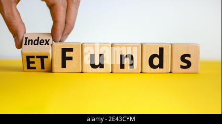 Fonds indiciels vs symbole ETF. Homme d'affaires transforme un cube et change les mots « ETF » en « Index funds ». Belle table jaune, fond blanc, espace de copie. Bus Banque D'Images