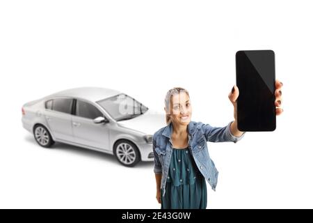 Jeune femme avec une voiture argentée tenant un téléphone portable en face de la caméra, isolée sur fond blanc Banque D'Images