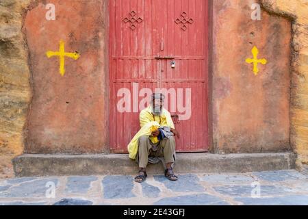 Prêtre assis avec croix devant l'église Rock-hewn Chirkos à Wukro, Tigray, Ethiopie Banque D'Images